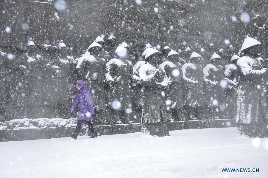 A citizen walks past sculptures in snow in Jilin City, northeast China's Jilin Province, March 27, 2013. (Xinhua/Wang Mingming)