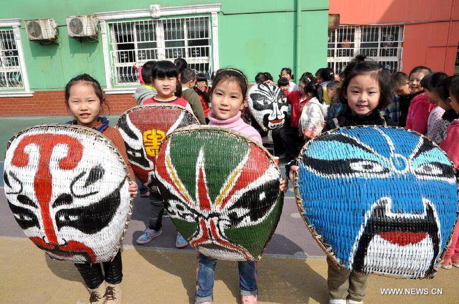 Children present the Beijing Opera facial masks drawn by themselves at a kindergarten at Handan City, north China's Hebei Province, March 27, 2013, the World Theatre Day. Children here drew the facial masks on used winnowing pans to learn more about traditional drama culture. (Xinhua/Hao Qunying) 