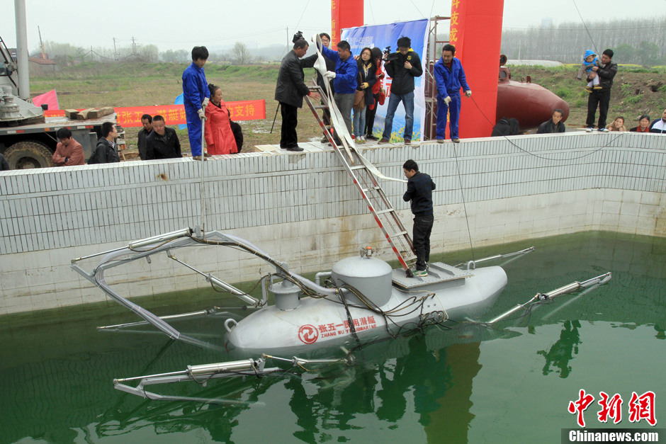 Zhang Wuyi gives instructions to his co-workers to move the newly developed unmanned underwater fishing device out of the workshop for an underwater testing in Wuhan on March 26, 2013. The “civil submarine” is equipped with a remote control and a camera for picking up image underwater. (Photo by Zhang Chang/ Chinanews.com)