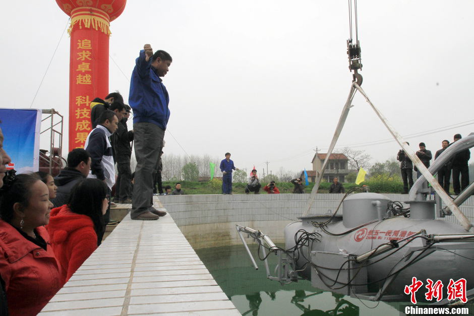 Zhang Wuyi gives instructions to his co-workers to move the newly developed unmanned underwater fishing device out of the workshop for an underwater testing in Wuhan on March 26, 2013. The “civil submarine” is equipped with a remote control and a camera for picking up image underwater. (Photo by Zhang Chang/ Chinanews.com)