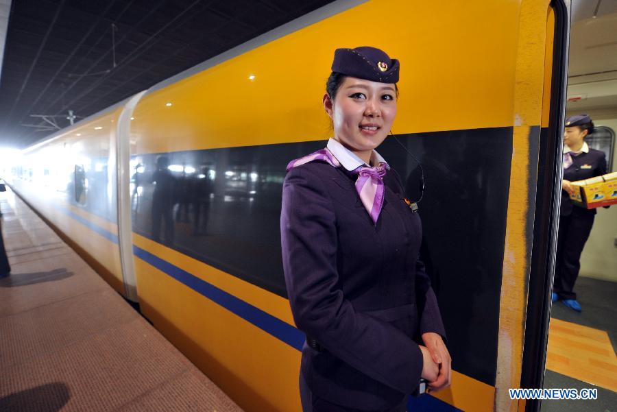 An attendant stands next to a bullet train when a test run of the Nanjing-Hangzhou High-Speed Railway ends at Nanjing South Railway Station in Nanjing, capital of east China's Jiangsu Province, March 28, 2013. The new Nanjing-Hangzhou High-Speed Railway is a supplement to railway travelling within China's Yangtze River Delta. The 249-kilometer rail line will reduce travel time from Nanjing to Hangzhou to about an hour. (Xinhua/Wang Dingchang)
