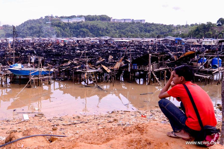 A man looks at the remains of the wooden houses after a fire in Kota Kinabalu, Malaysia, March 28, 2013. A fire engulfed over 400 wooden houses on the sea on Wednesday, leaving more than 3,000 people homeless and dozens injured. (Xinhua) 