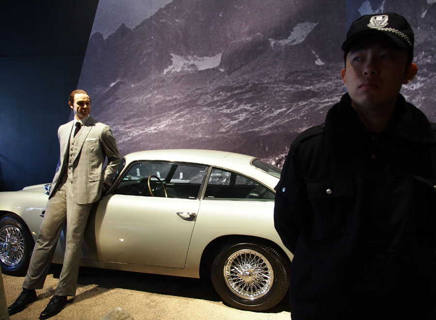 A security guard stands by James Bond's car at an exhibition in Shanghai, March 28, 2013. A global exhibition on the vintage series of 007 movies was held in Shanghai, March 28, 2013 to celebrate 007's 50th anniversary. From its first movie Dr. No in 1962 to the latest Skyfall in 2012, 23 movies have been screened and widely appreciated throughout the world. The exhibition will open to the public for three months, and Shanghai is its first stop in Asia. (Xinhua)