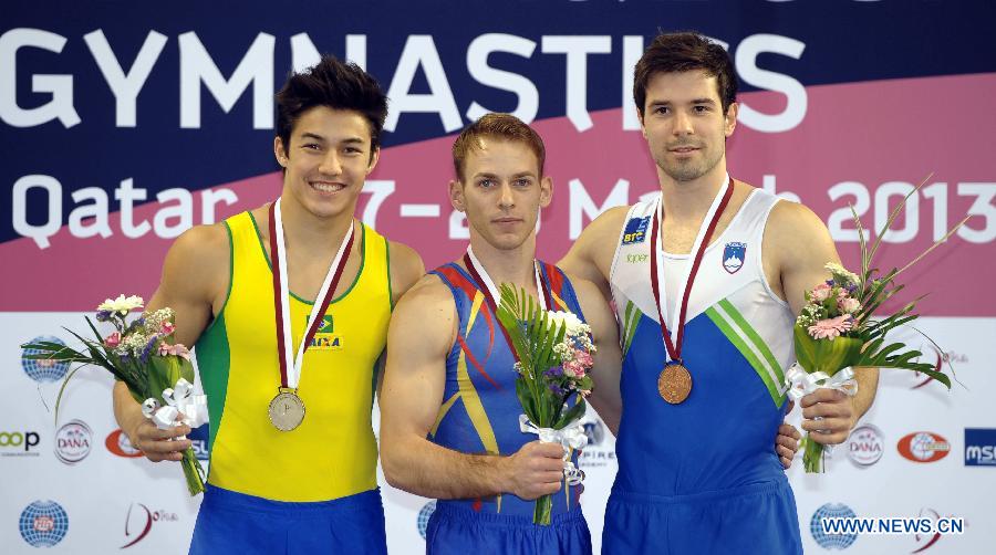 Gold medalist Flavius Koczi of Romania(C), silver medalist Arthur Oyakawa (L) of Brazil and bronze medalist Rok Klavora of Slovenia pose for a photo during the victory ceremony for Men's Floor enent at the FIG Artistic Gymnastics World Challenge cup in Doha, capital of Qatar, March 28, 2013. (Xinhua/Chen Shaojin)