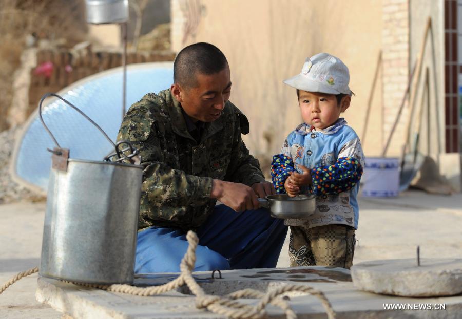 Villager Du Weibin washes hands for his child beside a water well in Qingshui Village of Lujiagou Township in Dingxi City, northwest China's Gansu Province, March 28, 2013. A drought lingering Gansu Province has caused 650,000 people lack of drinking water. (Xinhua/Chen Bin)