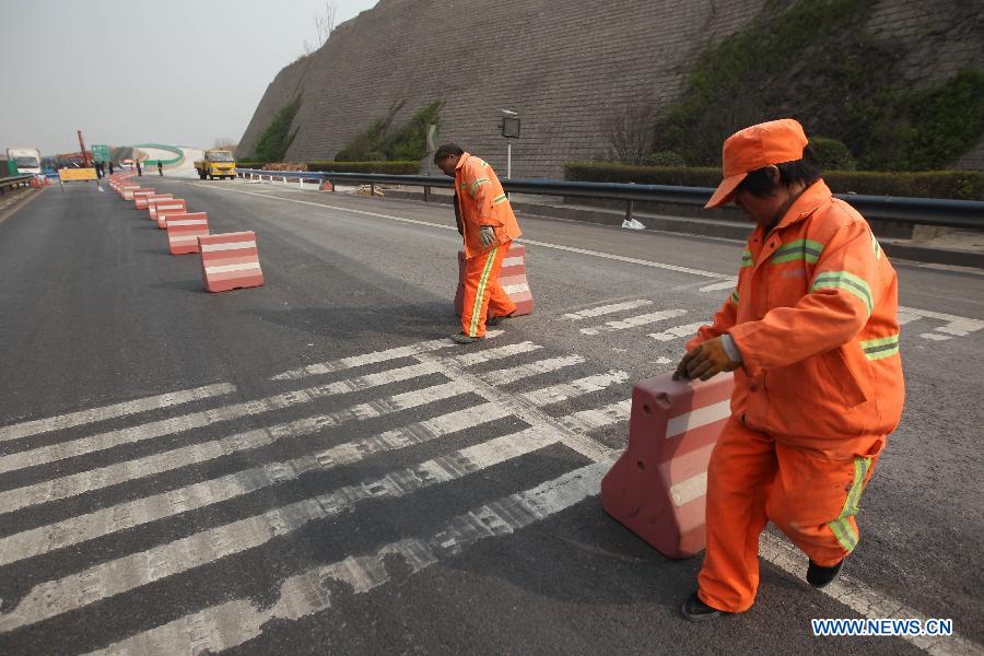 Staff members move traffic divided blocks so as to direct vehicles to run on the Yichang New Bridge on the Lianyugang-Horgos Highway in Sanmenxia City, central China's Henan Province, March 28, 2013. The Yichang New Bridge opened its two-way traffic on March 29 morning, after its construction passed the latest test. The 80-meter-long section of the old Yichang Bridge which was under repair collapsed after an explosion involving a fireworks-laden truck on Feb. 1. The accident claimed 13 lives. (Xinhua/Zhang Xiaoli)