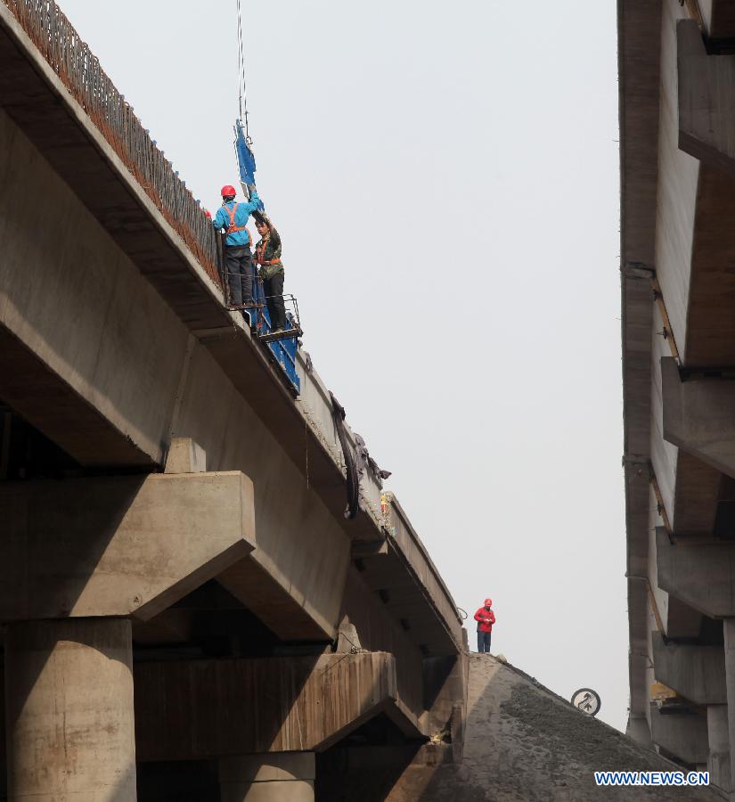 Workers repair the collapsed section of the southern lane of the old Yichang Bridge on the Lianyugang-Horgos Highway in Sanmenxia City, central China's Henan Province, March 28, 2013. The Yichang New Bridge opened its two-way traffic on March 29 morning, after its construction passed the latest test. The 80-meter-long section of the old Yichang Bridge which was under repair collapsed after an explosion involving a fireworks-laden truck on Feb. 1. The accident claimed 13 lives. (Xinhua/Zhang Xiaoli) 
