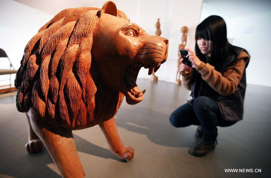 A visitor takes pictures of a wood sculpture at the African Wood Sculpture Collection exhibition in Nanjing, capital of east China's Jiangsu Province, March 29, 2013. The exhibition kicking off on Friday displays near 600 wood carving works from dozens of countries in the sub-Saharan Africa. (Xinhua/Wang Xin) 