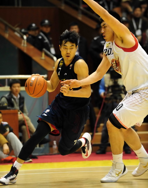 A player of Guangdong passes the ball as he is defended by a Shandong guard during the final of their CBA basketball game in Jinan, East China's Shandong province, March 29, 2013. [Wu Jun / chinadaily.com.cn]
