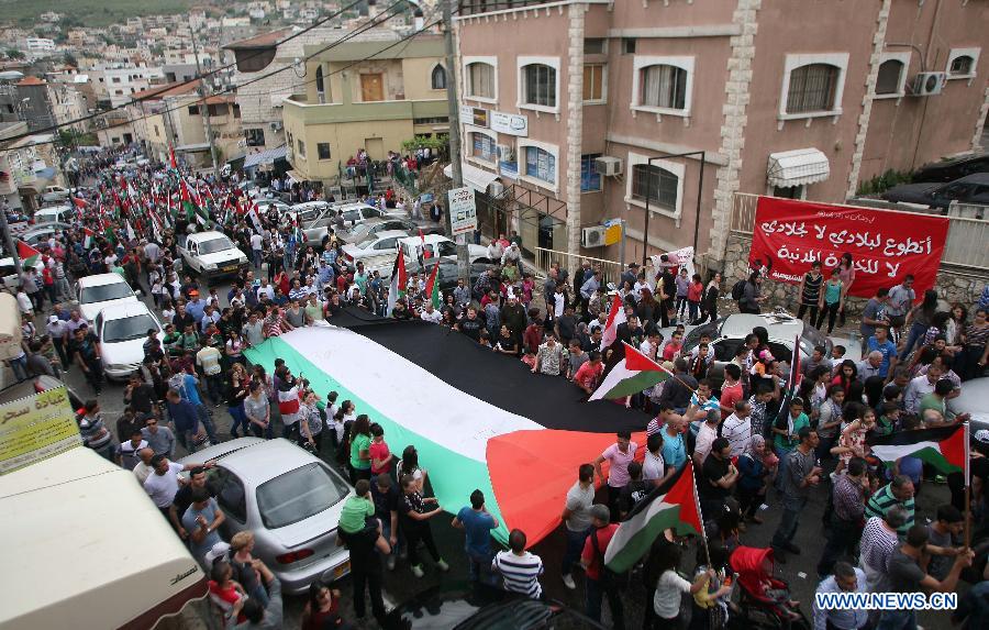Israeli Arabs carry a huge Palestinian flag during a demonstration marking Land Day in Israeli northern town of Sakhnin on March 30, 2013. Land Day is the annual commemoration of protests in 1976 against Israel's appropriation of Arab-owned land in Galilee. (Xinhua/Muammar Awad)