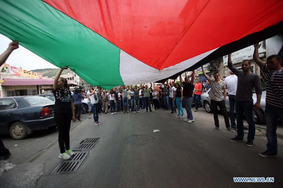 Israeli Arabs carry a huge Palestinian flag during a demonstration marking Land Day in Israeli northern town of Sakhnin on March 30, 2013. Land Day is the annual commemoration of protests in 1976 against Israel's appropriation of Arab-owned land in Galilee. (Xinhua/Muammar Awad)