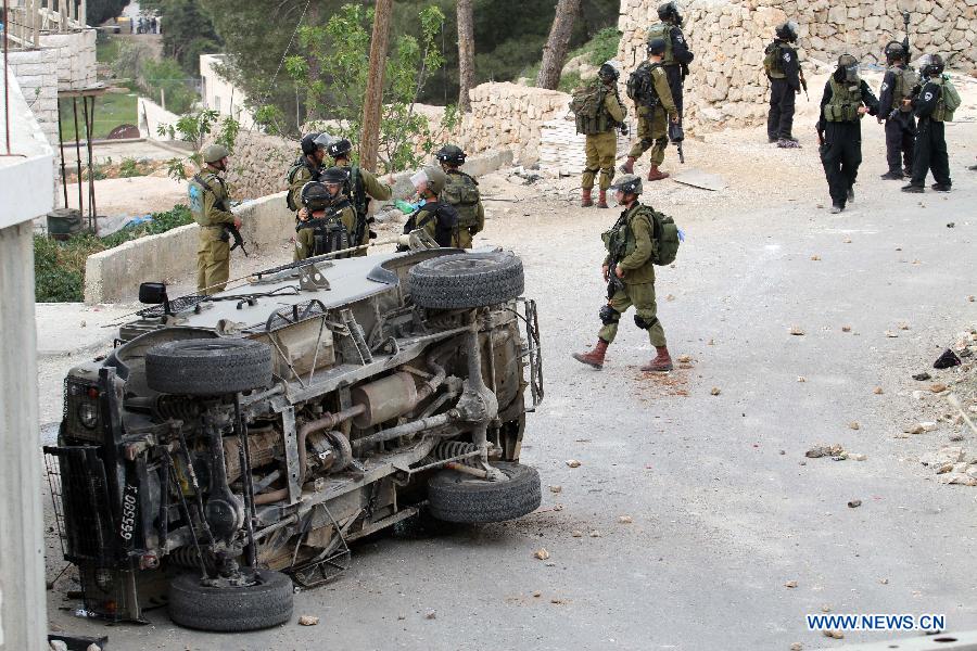 An Israeli army vehicle is seen inverted during clashes in the West Bank village of Al-Khader near Bethlehem on March 30, 2013. Riots broke out Saturday across the West Bank on the Palestinian Land Day, leaving two Israeli soldiers and one Israeli toddler lightly wounded. (Xinhua/Luay Sababa)