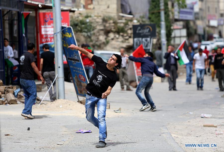 A Palestinian protester hurls stones towards Israeli soldiers at Qalandiya checkpoint near the West Bank city of Ramallah on March 30, 2013. Land Day commemorates the killing of six Palestinians by Israeli security forces in 1976 during a protest against the expropriation of their lands by the Israeli government in the northern Galilee region. (Xinhua/Fadi Arouri) 