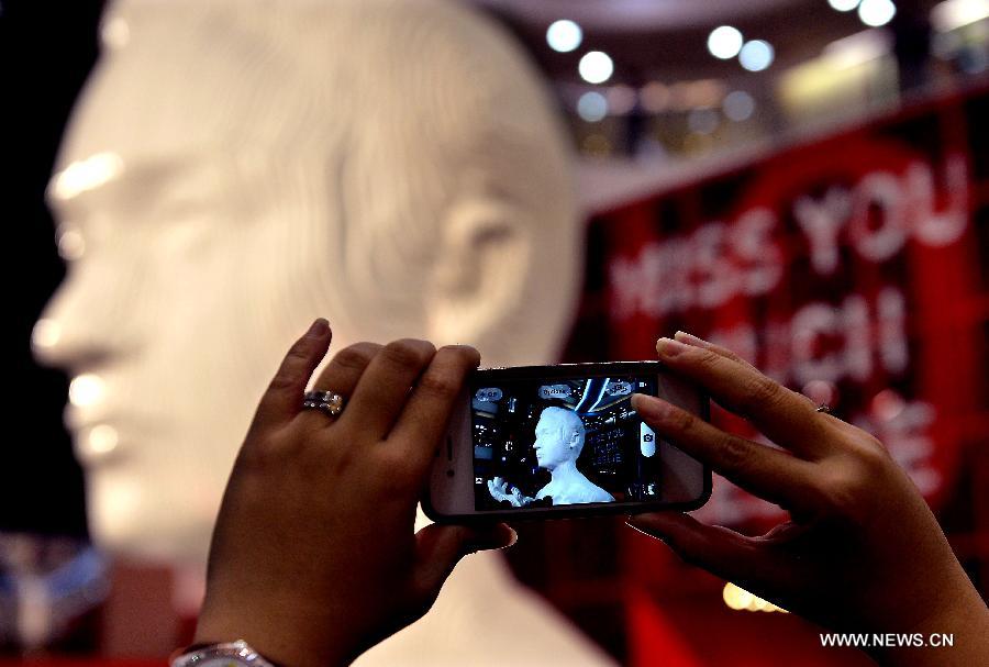 A fan takes a photo of a five-metre-high sculpture of late Hong Kong singer Leslie Cheung at an exhibition for paying tribute to Cheung in Hong Kong, south China, March 30, 2013. The exhibition is held to mark the 10th anniversary of the death of Leslie Cheung, who leapt to his death from a hotel in Hong Kong on April 1, 2003. A total of 1,900,119 origami cranes, folded by fans around the world, are displayed inside a giant red cube, which broke the Guinness World Record as "the largest display of origami cranes". (Xinhua/Chen Xiaowei)