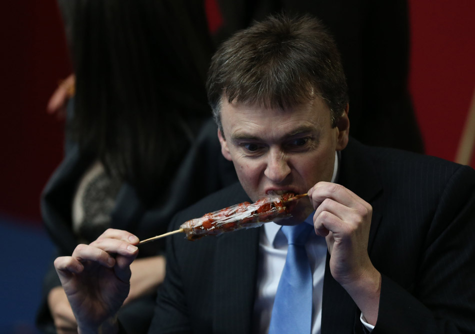 Jason Ferguson, chairman of the World Professional Billiards and Snooker Association (WPBSA) tastes candied fruits offered by students on March 24, 2013. Players in the 2013 World Snooker China Open came to the Capital Institute of Physical Education to communicate with snooker fans on campus. (Xinhua/Meng Yongmin)