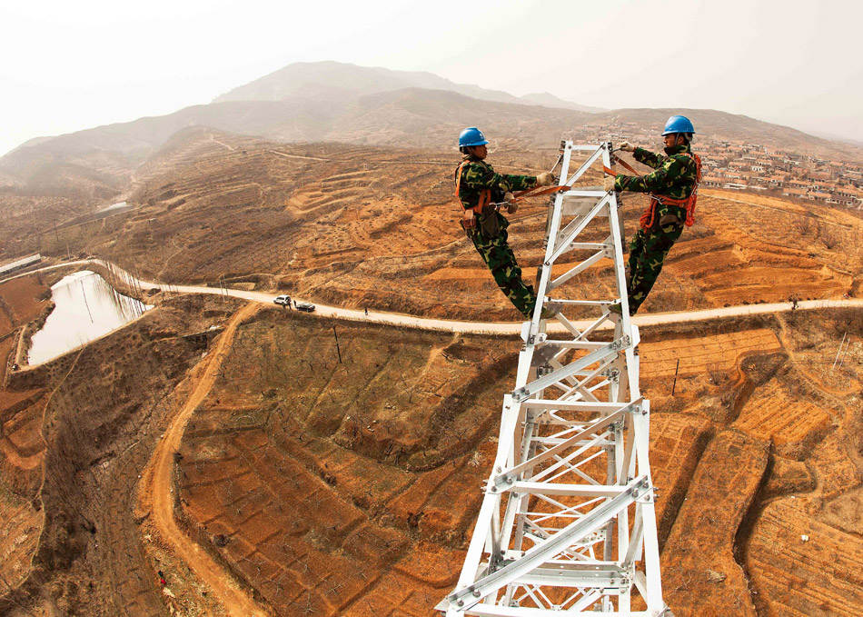 Workers operate on the No. 67 Tower of electricity transmission and distribution construction in Mengyin county of Shandong on March 25, 2013. (Xinhua/Tian Shichao)
