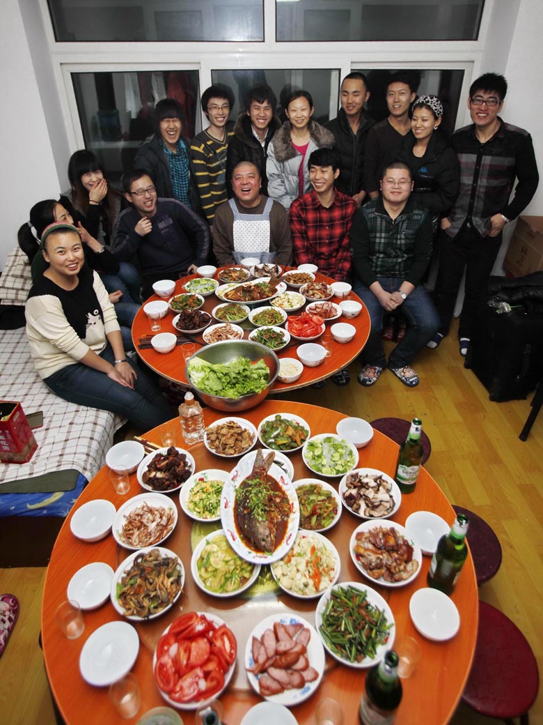 Gu Feng (middle) has dinner with the college students who have been supported by him in his home in Harbin on Jan. 17, 2013. Gu Feng, 43, an ordinary worker with Qinhuangdao branch of Bank of China, has provided financial support to 38 poor college students in seven years. (Xinhua/Yang Shiyao)