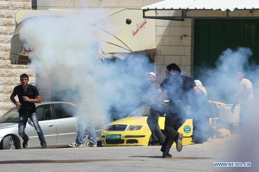 Palestinian protesters take cover from tear gas fired by Israeli soldiers during clashes in the West Bank village of Al-Maasarah, near Bethlehem on March 29, 2013. (Xinhua/Luay Sababa) 