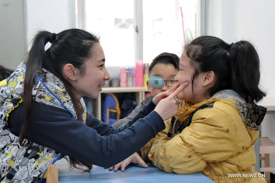 Teacher Lin Jixiang (L) provides training for an autistic child at Xingyu School in Fuzhou, capital of southeast China's Fujian Province, March 28, 2013. The Xingyu School, offically opened to public in February this year, is a nine-year compulsory education school founded specifically for autistic children. It combines the characteristics of normal primary schools and autism rehabilitation centers, and provides both linguistic and behavior trainings to autistic children for their better intergration into the society in the future. (Xinhua/Lin Shanchuan) 