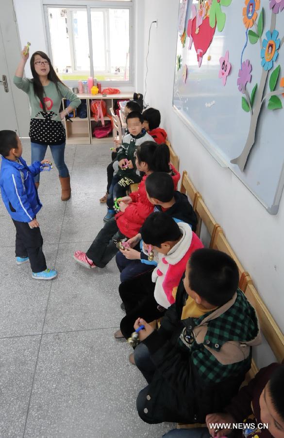 Teacher Liu Yan (2nd L) provides music rehabilitation training for autistic children at Xingyu School in Fuzhou, capital of southeast China's Fujian Province, April 1, 2013. The Xingyu School, offically opened to public in February this year, is a nine-year compulsory education school founded specifically for autistic children. It combines the characteristics of normal primary schools and autism rehabilitation centers, and provides both linguistic and behavior trainings to autistic children for their better intergration into the society in the future. (Xinhua/Lin Shanchuan)