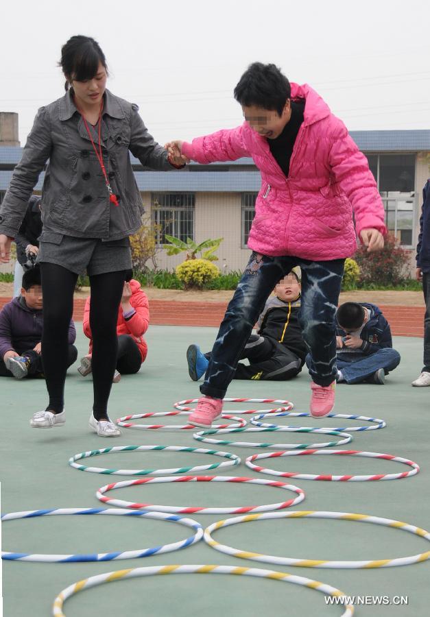 A teacher trains an autistic child for exercise at Xingyu School in Fuzhou, capital of southeast China's Fujian Province, March 28, 2013. The Xingyu School, offically opened to public in February this year, is a nine-year compulsory education school founded specifically for autistic children. It combines the characteristics of normal primary schools and autism rehabilitation centers, and provides both linguistic and behavior trainings to autistic children for their better intergration into the society in the future. (Xinhua/Lin Shanchuan)