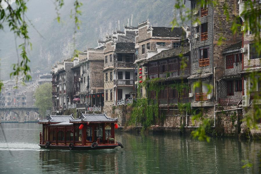 An tourism boat move on the Wuyang River in Zhenyuan County, southwest China's Guizhou Province, March 31, 2013. The county could date back 2,280 years with the Wuyang River running through it. As many ancient style architectures were built along the river, the ancient town was dubbed as "Oriental Venice" by tourists. (Xinhua/Hu Yan)