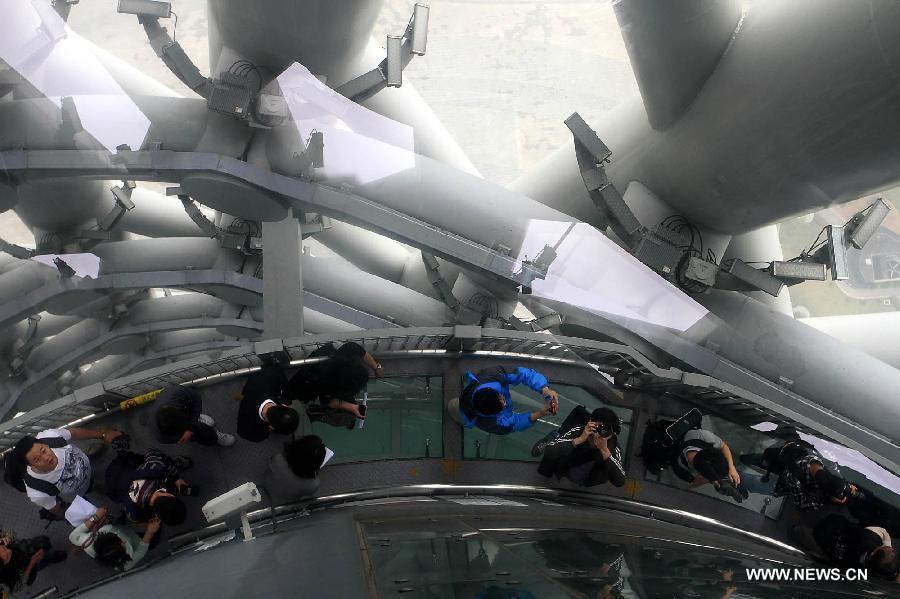 Visitors walk along the Spider Walk in the Canton Tower in Guangzhou, capital of south China's Guangdong Province, April 2, 2013. The 1,000-meter-long Spider Walk locates at the 168-meter to 334.4-meter height of Canton Tower, with a transparent floor made up of 90 pieces of glasses. Visitors would get a general view of the scenery of Guangzhou City from the Spider Walk. (Xinhua/Shen Dunwen)