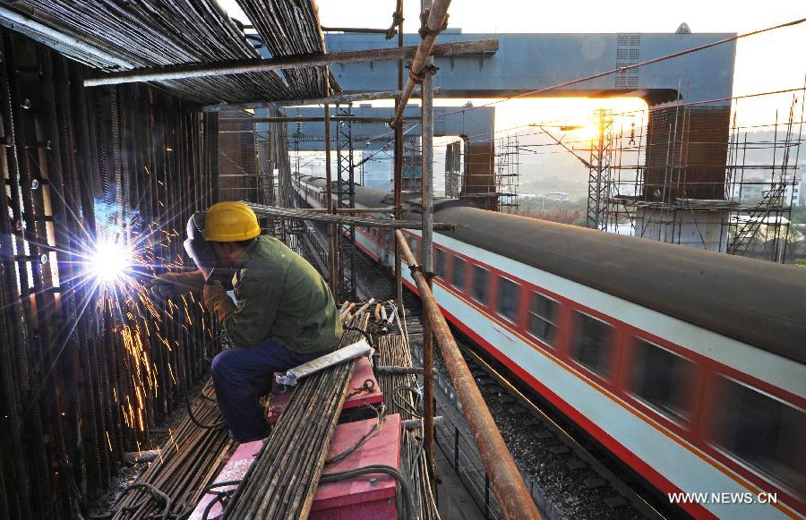 A train drives by the construction site of the Yiwu section of the Hangzhou-Changsha High-speed Rail on the Dongte Bridge in Yiwu, east China's Zhejiang Province, Dec. 6, 2012. The 920-kilometer-long Hangzhou-Changsha High-speed Rail would shorten the travelling time between east China's Hangzhou and central China's Changsha from 6.3 hours to 3 hours once completed. (Xinhua/Tan Jin)