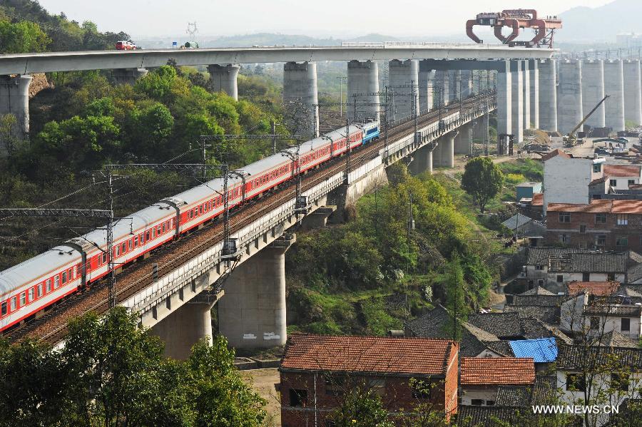 A train moves close to the construction site of the Yiwu section of the Hangzhou-Changsha High-speed Rail on the Dongte Bridge in Yiwu, east China's Zhejiang Province, April 2, 2013. The 920-kilometer-long Hangzhou-Changsha High-speed Rail would shorten the travelling time between east China's Hangzhou and central China's Changsha from 6.3 hours to 3 hours once completed. (Xinhua/Tan Jin)