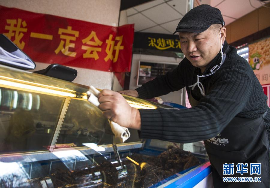 Qi Fayi wipes the counter in his snack shop.  (Xinhua Photo/ Wang Fei)
