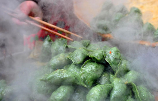 A street vendor on Yincheng street, Dexing city, Jiangxi province removes boiled Ai Fruit from a pot of boiling water on March 27.2013. As Qingming Festival (Tomb Sweeping Day) approaches, the residents in Dexing city, Jiangxi province prepare Ai Fruit, which will be eaten during Qingming Festival. Ai Fruit has a sweet and salty taste also referred to as Sweet Green Rice Ball, Qingming Fruit. The delicacy is made from glutinous rice stuffed with Ai grass or gnaphalium affine. Many people feel that not only is Ai Fruit sacred food for the Qingming Festival, but also a specialty of traditional Chinese food found in rural areas in China.  (Xinhua)