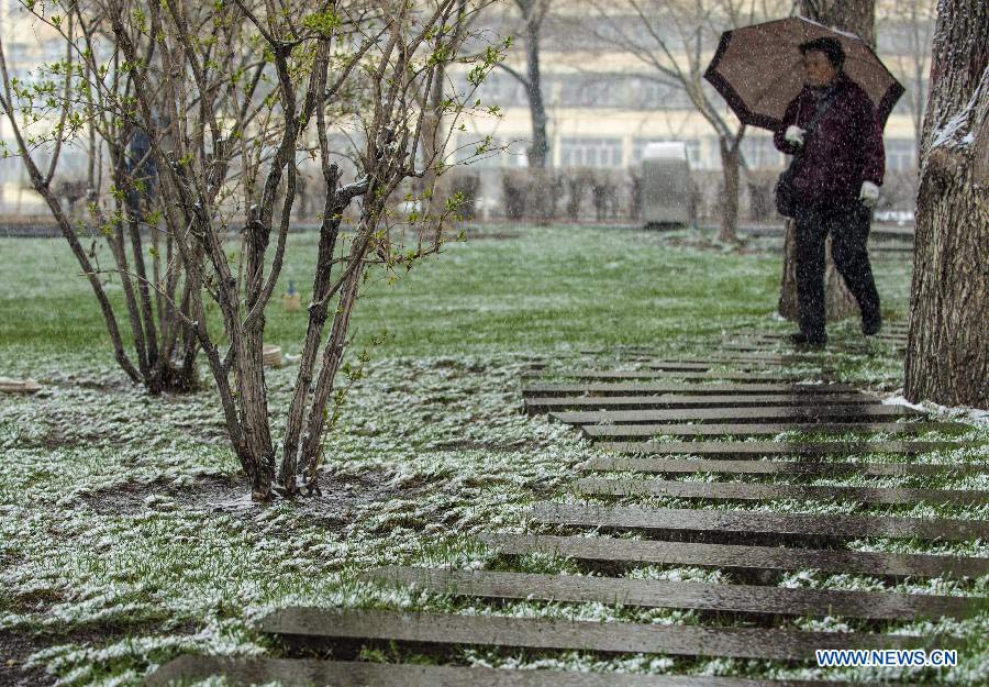 A woman holds an umbrella to shelter from sleet in Urumqi, capital of northwest China's Xinjiang Uygur Autonomous Region, April 3, 2013. A sleet hit the capital city of Xinjiang on Wednesday in the wake of sharp temperature drop. (Xinhua/Wang Fei)