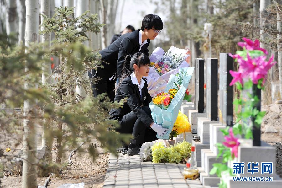 Funeral directors Wang Na (L) and Lu Yufei place flowers besides a tombstone as they pay respect to the dead in a cemetery in Yinchuan city, capital of Northwest China's Ningxia Hui autonomous region, on April 2, 2013. (Photo/Xinhua) 