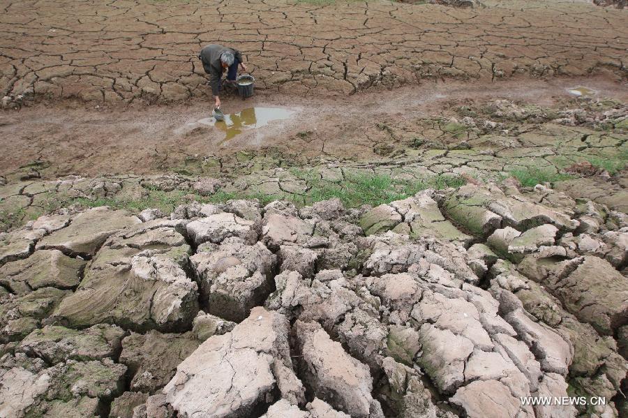 Fu Xianxing, 70, a villager of Shichanggou Village, gets water from a dried river bed in Yongxing Town of Suining City in southwest China's Sichuan Province, April 2, 2013. A severe drought has lingered over Suining since last winter, causing shortage of drinking water in some towns of the city. (Xinhua/Zhong Min)