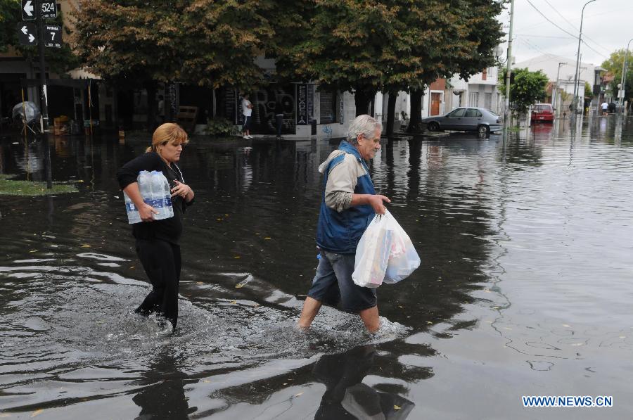 Two residents walk through a flooded area after a storm, in Tolosa, La Plata, 63 km south of Buenos Aires, Argentina, on April 3, 2013. At least 46 people have died due to heavy storms in La Plata, and another 3,000 have been evacuated. (Xinhua/TELAM) 