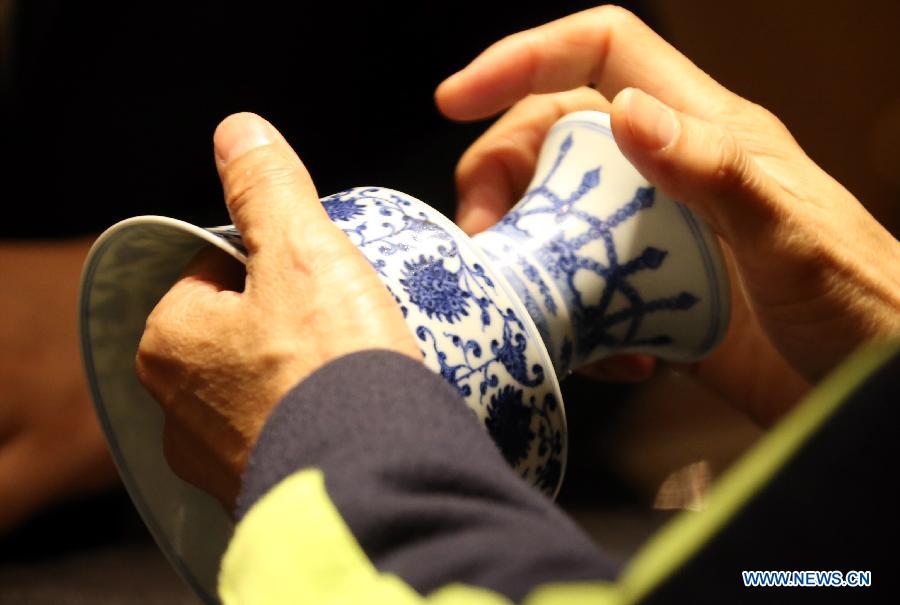 A buyer looks at a ceramic cup from Qing Dynasty (1644-1911) during the preview of the Hong Kong 2013 Spring Auctions held by China Guardian Auctions Co. Ltd in Hong Kong, south China, April 3, 2013. The two-day auctions will start on April 4, with over 300 pieces of paintings and calligraphy as well as ceramic artworks. (Xinhua/Li Peng)