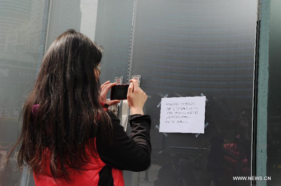 A woman takes photos of a closing notice pasted on the closed door of Nokia's flagship store in Nanjing East Road in Shanghai, east China, April 3, 2013. The retail store, which is Nokia's only stand-alone flagship store and the largest around the world, was found closed in recent days. (Xinhua/Lai Xinlin) 