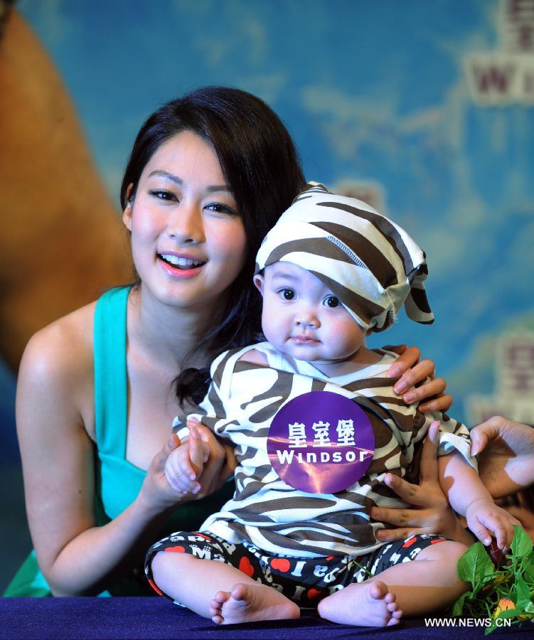 Pop star Eliza Sam poses for a photo with a baby during a crawl competition held in a shopping mall in Hong Kong, south China, April 4, 2013. Many parents took their children to the event here on Thursday. (Xinhua/Lui Siu Wai)