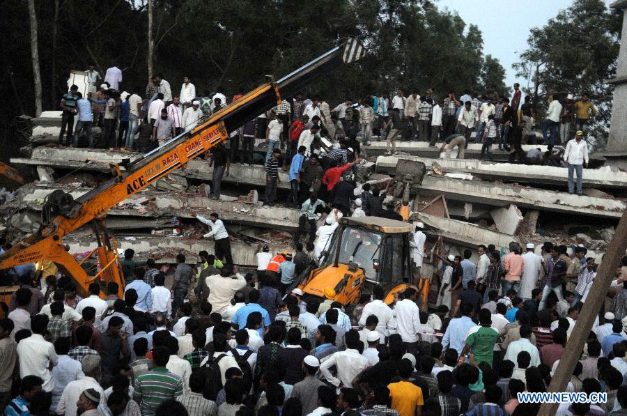 People gather as rescuers look for trapped people after a building collapsed in Thane, Mumbai, India, April 4, 2013. At least 9 people died and over 40 people were injured when an under-construction residential building collapsed on Thursday evening, local media reported. (Xinhua/Stringer)