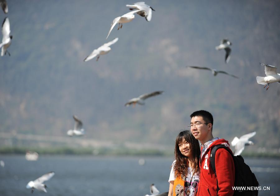 Visitors pose for photo with black-headed gulls by the Haigeng Dam in Kunming, capital of southwest China's Yunnan Province, April 4, 2013, the first day of the three-day Qingming Festival holidays. (Xinhua/Qin Lang)