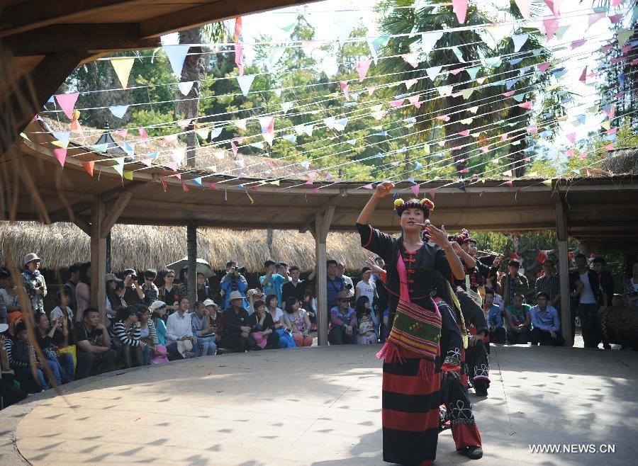 Visitors watch traditional performance of Wa ethnic group at Ethnic Villages in Kunming, capital of southwest China's Yunnan Province, April 4, 2013, the first day of the three-day Qingming Festival holidays. (Xinhua/Qin Lang)