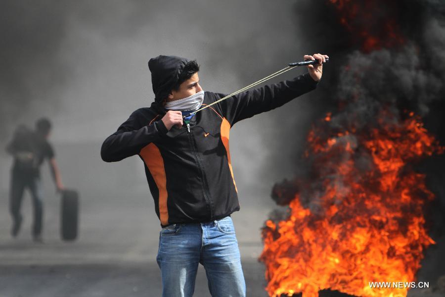 A Palestinian youth uses catapult to lunch stones toward Israeli soldiers during clashes in the West Bank village of al-Khader near city of Bethlehem, April 5, 2013(Xinhua/Luay Sababa)