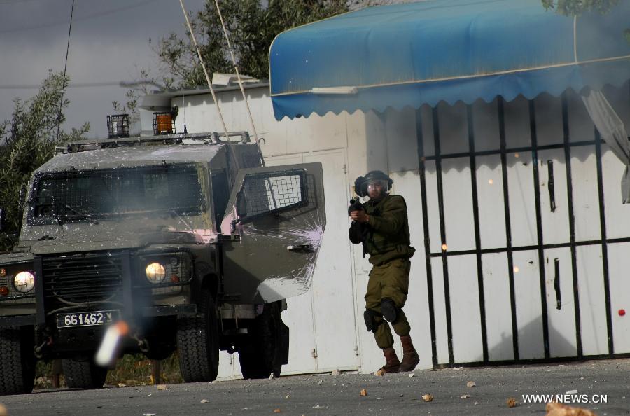 An Israeli soldier fires at Palestinian protesters during clashes in the West Bank city of Hebron on April 5, 2013. (Xinhua/Mamoun Wazwaz)