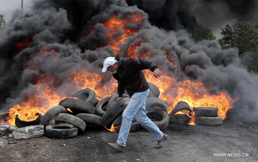 A Palestinian protester puts a burning tire to close the road during a protest against the expanding of Jewish settlements in Kufr Qadoom village near the West Bank city of Nablus on Apr. 5, 2013 (Xinhua/Nidal Eshtayeh)