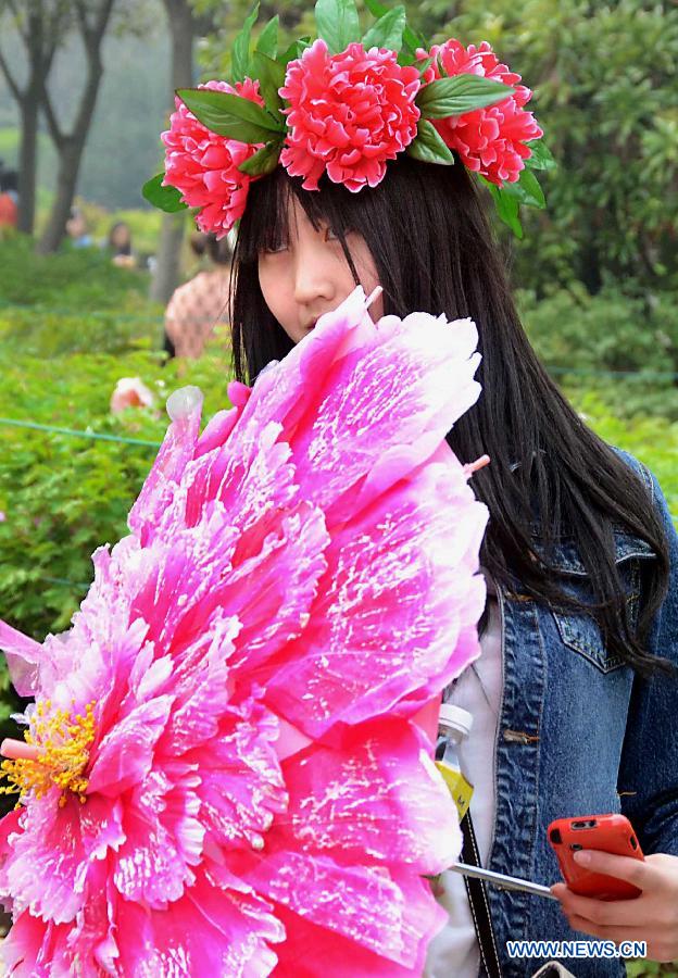 A woman wearing a "peony hat" and holding a "poeny umbrella" poses for pictures at a park in Luoyang, central China's Henan Province, April 5, 2013. Poeny hats made of paper or tough silk have become popular in Luoyang, which was once an imperial capital for 13 dynasties through the Chinese history and is famous for its poenies. (Xinhua/Wang Song)