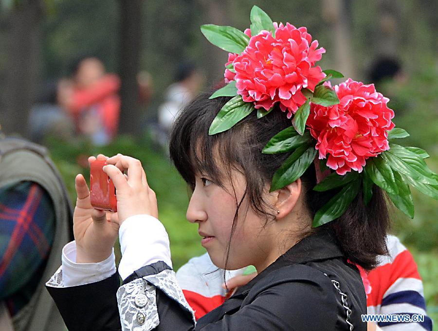 A woman wearing a "peony hat" takes pictures at a park in Luoyang, central China's Henan Province, April 5, 2013. Poeny hats made of paper or tough silk have become popular in Luoyang, which was once an imperial capital for 13 dynasties through the Chinese history and is famous for its poenies. (Xinhua/Wang Song)