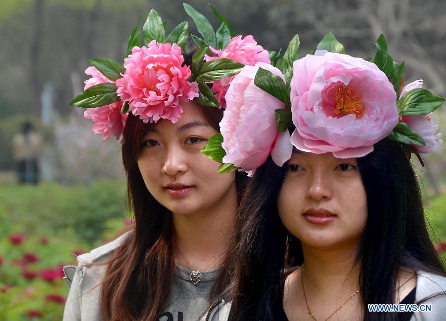 Two women wearing "peony hats" enjoy themselves at a park in Luoyang, central China's Henan Province, April 5, 2013. Poeny hats made of paper or tough silk have become popular in Luoyang, which was once an imperial capital for 13 dynasties through the Chinese history and is famous for its poenies. (Xinhua/Wang Song)