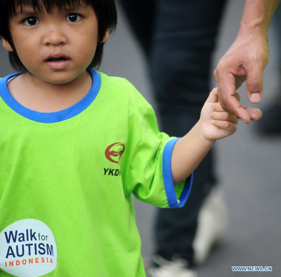 A child holding his father's hand joins in the annual Walk for Autism 2013 in Jakarta, Indonesia, April 6, 2013. Walk for Autism is one part of its autism awareness campaign. (Xinhua/Veri Sanovri)