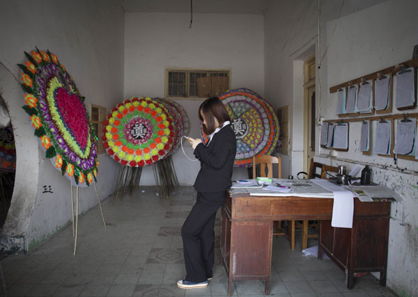 Yan Jing is waiting in the wreath store of the mortuary house. [Photo by Gao Erqiang / China Daily] 