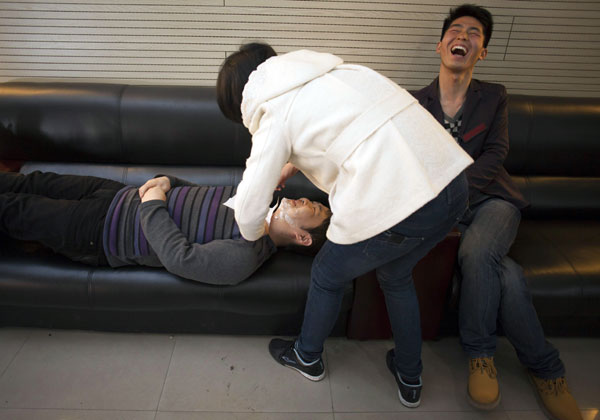 Feng Shuozhi (left) acts as a model for Zhang Weixue (middle) to apply makeup, but Zhang discovers she can only shave a person who is lying down. Ren Wanzhi is laughing at her clumsiness. [Photo by Gao Erqiang / China Daily] 